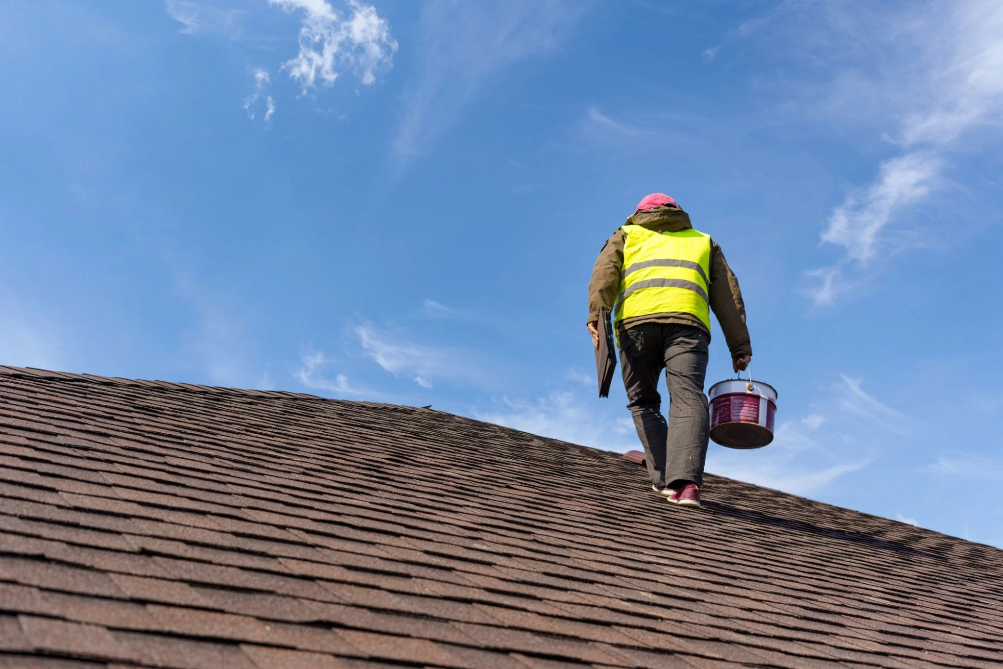 Professional roofer inspecting storm damaged roof tiles with Melbourne skyline in background